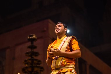 Varanasi, Uttar Pradesh, Hindistan - 20 Kasım 2022: Ganga aarti, Dashashwamedh ghat 'ında geleneksel Hint ayinleriyle akşam üzeri genç rahibin kutsal nehir çetelerini sergilediği portre.