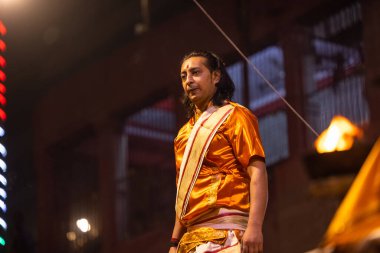 Varanasi, Uttar Pradesh, Hindistan - 20 Kasım 2022: Ganga aarti, Dashashwamedh ghat 'ında geleneksel Hint ayinleriyle akşam üzeri genç rahibin kutsal nehir çetelerini sergilediği portre.