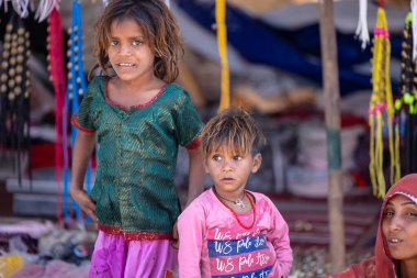 Puşkar, Rajasthan, Hindistan - 05 Kasım 2022: Puşkar Fuarı, fuar sırasındaki etkinlikleri izleyen renkli elbiseli genç çocukların portresi.