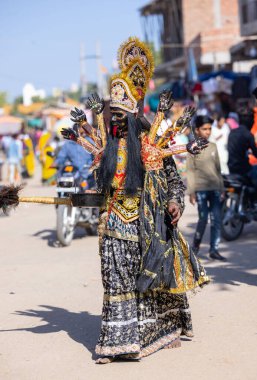 Puşkar, Rajasthan, Hindistan - Kasım 05 2022: Tanrıça Kali kılığında bir sanatçının portresi ve fuar sırasında Pushkar sokaklarında dolaşan siyah bir yüz resmi. Yüze ve göze seçici odaklanma.