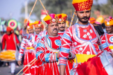 Bikaner, Rajasthan, Hindistan - 13 Ocak 2023: Deve Festivali, geleneksel renkli rajasthani elbisesi giyen renkli türbanlı bir müzik enstrümanı çalan bir Rajasthani erkek sanatçı grubu.