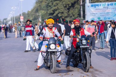 Bikaner, Rajasthan, Hindistan - 13 Ocak 2023: Deve Festivali, geçit töreninde geleneksel beyaz rajasthani elbisesi ve türban mermisi giyen sakallı ve bıyıklı genç bir Rajasthani erkeğinin portresi