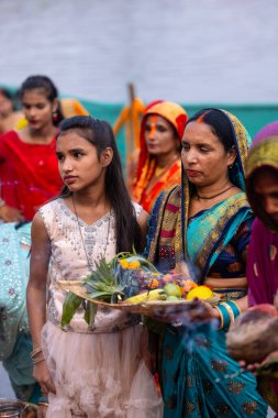 Gaziabad, Uttar Pradesh, Hindistan - 30 Ekim 2022: Chhas Puja, Hintli kadın dindar gün batımında Lord Sun 'a ibadet etmek için nehirde dururken Chhas puja ayini yapıyor..