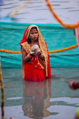 Gaziabad, Uttar Pradesh, Hindistan - 30 Ekim 2022: Chhas Puja, Hintli kadın dindar gün batımında Lord Sun 'a ibadet etmek için nehirde dururken Chhas puja ayini yapıyor..