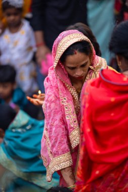 Gaziabad, Uttar Pradesh, Hindistan - 30 Ekim 2022: Chhas Puja, Hintli kadın dindar gün batımında Lord Sun 'a ibadet etmek için nehirde dururken Chhas puja ayini yapıyor..