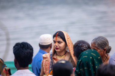 Gaziabad, Uttar Pradesh, Hindistan - 30 Ekim 2022: Chhas Puja, Hintli kadın dindar gün batımında Lord Sun 'a ibadet etmek için nehirde dururken Chhas puja ayini yapıyor..