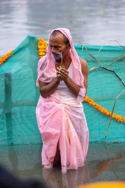 Ghaziabad, Uttar Pradesh, India - October 30 2022: Chhath Puja, Indian hindu female devotee performing rituals of chhath puja while standing in river to worship lord sun during sunset. clipart