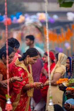 Gaziabad, Uttar Pradesh, Hindistan - 30 Ekim 2022: Chhas Puja, Hintli kadın dindar gün batımında Lord Sun 'a ibadet etmek için nehirde dururken Chhas puja ayini yapıyor..