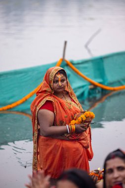 Gaziabad, Uttar Pradesh, Hindistan - 30 Ekim 2022: Chhas Puja, Hintli kadın dindar gün batımında Lord Sun 'a ibadet etmek için nehirde dururken Chhas puja ayini yapıyor..