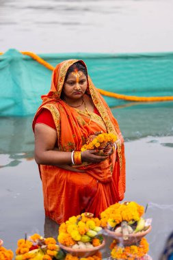 Gaziabad, Uttar Pradesh, Hindistan - 30 Ekim 2022: Chhas Puja, Hintli kadın dindar gün batımında Lord Sun 'a ibadet etmek için nehirde dururken Chhas puja ayini yapıyor..