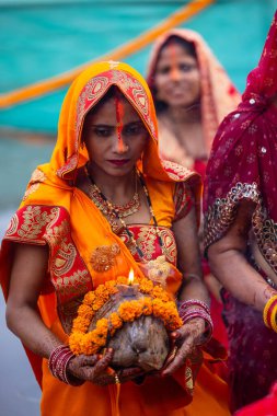 Ghaziabad, Uttar Pradesh, India - October 30 2022: Chhath Puja, Indian hindu female devotee performing rituals of chhath puja while standing in river to worship lord sun during sunset. clipart