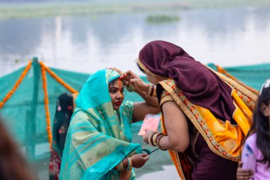 Gaziabad, Uttar Pradesh, Hindistan - 30 Ekim 2022: Chhas Puja, Hintli kadın dindar gün batımında Lord Sun 'a ibadet etmek için nehirde dururken Chhas puja ayini yapıyor..