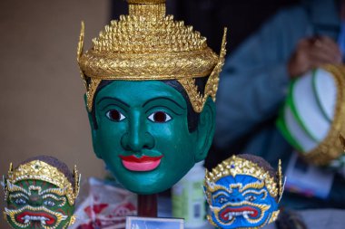 Handmade colorful tribal look face mask souvenir hanging on plain background. Selective focus on object.