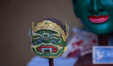 Handmade colorful tribal look face mask souvenir hanging on plain background. Selective focus on object.