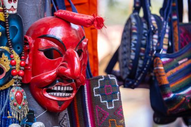 Handmade colorful tribal look face mask souvenir hanging on plain background. Selective focus on object.