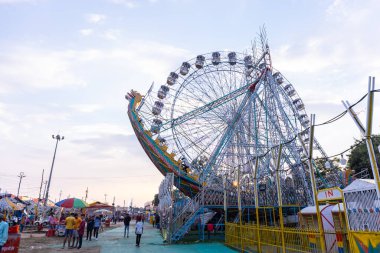 Gaziabad, Uttar Pradesh, Hindistan - 05 Ekim 2022: Geceleyin gerçekleşen dussehra fuarı sırasında turistler panayırda ortak tekerlek sürüşünün keyfini çıkarıyorlar.