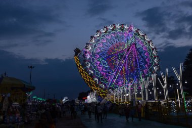 Gaziabad, Uttar Pradesh, Hindistan - 05 Ekim 2022: Geceleyin gerçekleşen dussehra fuarı sırasında turistler panayırda ortak tekerlek sürüşünün keyfini çıkarıyorlar.