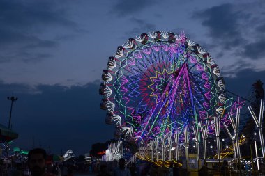 Gaziabad, Uttar Pradesh, Hindistan - 05 Ekim 2022: Geceleyin gerçekleşen dussehra fuarı sırasında turistler panayırda ortak tekerlek sürüşünün keyfini çıkarıyorlar.