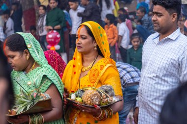 Gaziabad, Uttar Pradesh, Hindistan - 30 Ekim 2022: Chhas Puja, Hintli kadın dindar gün batımında Lord Sun 'a ibadet etmek için nehirde dururken Chhas puja ayini yapıyor..