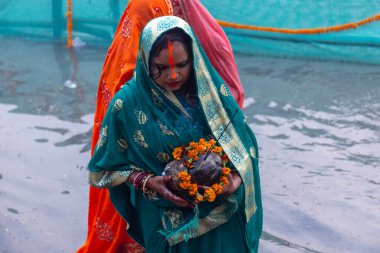 Gaziabad, Uttar Pradesh, Hindistan - 30 Ekim 2022: Chhas Puja, Hintli kadın dindar gün batımında Lord Sun 'a ibadet etmek için nehirde dururken Chhas puja ayini yapıyor..