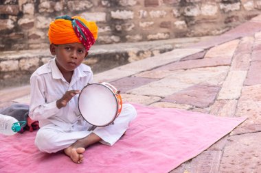 Jodhpur, Rajasthan, Hindistan - 25 Eylül 2021: Mehrangarh Kalesi, geleneksel Rajasthani elbisesiyle turistleri ağırlamak için müzik aleti çalan sanatçının portresi.