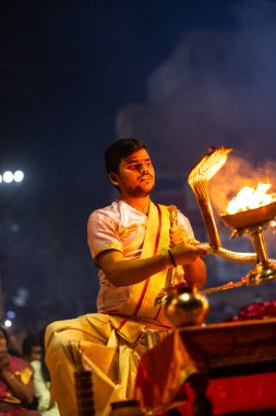Varanasi, Uttar Pradesh, Hindistan - 3 Mart 2023: Ganga aarti, Dashashwamedh ghat geleneksel elbise ve Hindu ayinleri ile kutsal nehir ganges akşam aarti performans genç rahip portresi