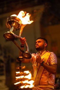 Varanasi, Uttar Pradesh, Hindistan - 3 Mart 2023: Ganga aarti, Dashashwamedh ghat geleneksel elbise ve Hindu ayinleri ile kutsal nehir ganges akşam aarti performans genç rahip portresi