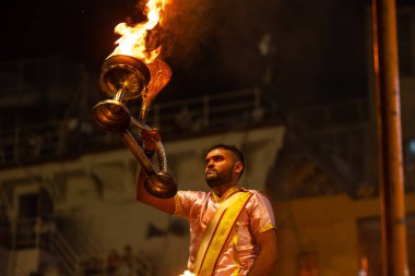Varanasi, Uttar Pradesh, Hindistan - 3 Mart 2023: Ganga aarti, Dashashwamedh ghat geleneksel elbise ve Hindu ayinleri ile kutsal nehir ganges akşam aarti performans genç rahip portresi