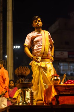 Varanasi, Uttar Pradesh, Hindistan - 3 Mart 2023: Ganga aarti, Dashashwamedh ghat geleneksel elbise ve Hindu ayinleri ile kutsal nehir ganges akşam aarti performans genç rahip portresi