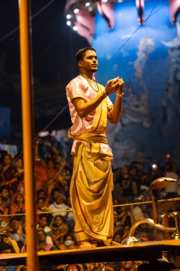 Varanasi, Uttar Pradesh, Hindistan - 3 Mart 2023: Ganga aarti, Dashashwamedh ghat geleneksel elbise ve Hindu ayinleri ile kutsal nehir ganges akşam aarti performans genç rahip portresi