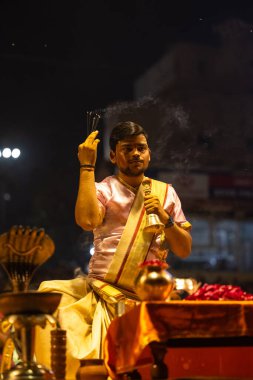 Varanasi, Uttar Pradesh, Hindistan - 3 Mart 2023: Ganga aarti, Dashashwamedh ghat geleneksel elbise ve Hindu ayinleri ile kutsal nehir ganges akşam aarti performans genç rahip portresi
