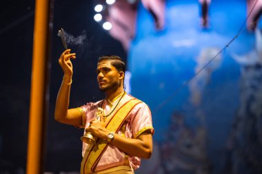 Varanasi, Uttar Pradesh, Hindistan - 3 Mart 2023: Ganga aarti, Dashashwamedh ghat geleneksel elbise ve Hindu ayinleri ile kutsal nehir ganges akşam aarti performans genç rahip portresi