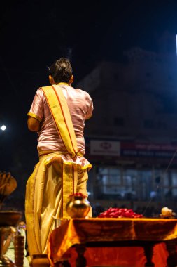 Varanasi, Uttar Pradesh, Hindistan - 3 Mart 2023: Ganga aarti, Dashashwamedh ghat geleneksel elbise ve Hindu ayinleri ile kutsal nehir ganges akşam aarti performans genç rahip portresi