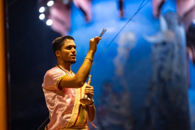 Varanasi, Uttar Pradesh, Hindistan - 3 Mart 2023: Ganga aarti, Dashashwamedh ghat geleneksel elbise ve Hindu ayinleri ile kutsal nehir ganges akşam aarti performans genç rahip portresi