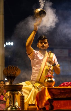Varanasi, Uttar Pradesh, Hindistan - 3 Mart 2023: Ganga aarti, Dashashwamedh ghat geleneksel elbise ve Hindu ayinleri ile kutsal nehir ganges akşam aarti performans genç rahip portresi