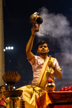 Varanasi, Uttar Pradesh, Hindistan - 3 Mart 2023: Ganga aarti, Dashashwamedh ghat geleneksel elbise ve Hindu ayinleri ile kutsal nehir ganges akşam aarti performans genç rahip portresi
