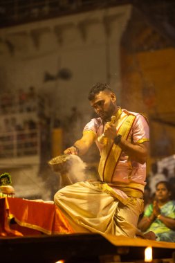 Varanasi, Uttar Pradesh, Hindistan - 3 Mart 2023: Ganga aarti, Dashashwamedh ghat geleneksel elbise ve Hindu ayinleri ile kutsal nehir ganges akşam aarti performans genç rahip portresi