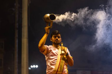 Varanasi, Uttar Pradesh, Hindistan - 3 Mart 2023: Ganga aarti, Dashashwamedh ghat geleneksel elbise ve Hindu ayinleri ile kutsal nehir ganges akşam aarti performans genç rahip portresi