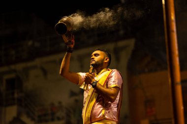 Varanasi, Uttar Pradesh, Hindistan - 3 Mart 2023: Ganga aarti, Dashashwamedh ghat geleneksel elbise ve Hindu ayinleri ile kutsal nehir ganges akşam aarti performans genç rahip portresi