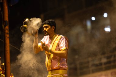 Varanasi, Uttar Pradesh, Hindistan - 3 Mart 2023: Ganga aarti, Dashashwamedh ghat geleneksel elbise ve Hindu ayinleri ile kutsal nehir ganges akşam aarti performans genç rahip portresi