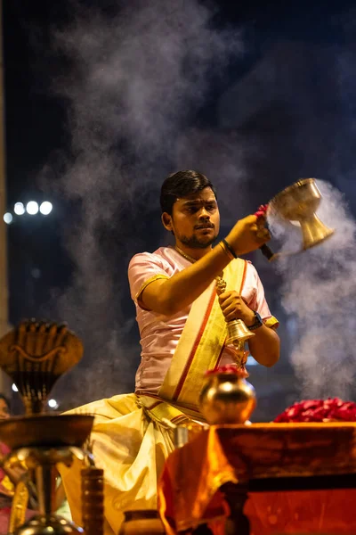 Varanasi, Uttar Pradesh, Hindistan - 3 Mart 2023: Ganga aarti, Dashashwamedh ghat geleneksel elbise ve Hindu ayinleri ile kutsal nehir ganges akşam aarti performans genç rahip portresi