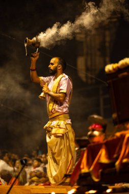 Varanasi, Uttar Pradesh, Hindistan - 3 Mart 2023: Ganga aarti, Dashashwamedh ghat geleneksel elbise ve Hindu ayinleri ile kutsal nehir ganges akşam aarti performans genç rahip portresi