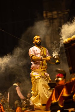 Varanasi, Uttar Pradesh, Hindistan - 3 Mart 2023: Ganga aarti, Dashashwamedh ghat geleneksel elbise ve Hindu ayinleri ile kutsal nehir ganges akşam aarti performans genç rahip portresi