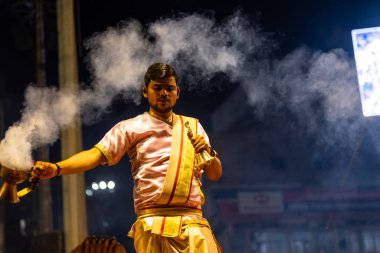 Varanasi, Uttar Pradesh, Hindistan - 3 Mart 2023: Ganga aarti, Dashashwamedh ghat geleneksel elbise ve Hindu ayinleri ile kutsal nehir ganges akşam aarti performans genç rahip portresi