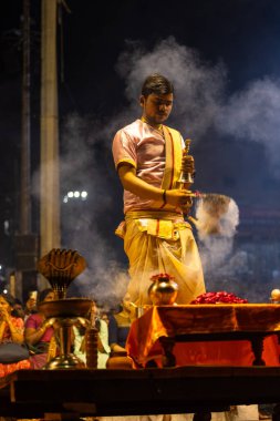 Varanasi, Uttar Pradesh, Hindistan - 3 Mart 2023: Ganga aarti, Dashashwamedh ghat geleneksel elbise ve Hindu ayinleri ile kutsal nehir ganges akşam aarti performans genç rahip portresi