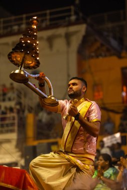 Varanasi, Uttar Pradesh, Hindistan - 3 Mart 2023: Ganga aarti, Dashashwamedh ghat geleneksel elbise ve Hindu ayinleri ile kutsal nehir ganges akşam aarti performans genç rahip portresi