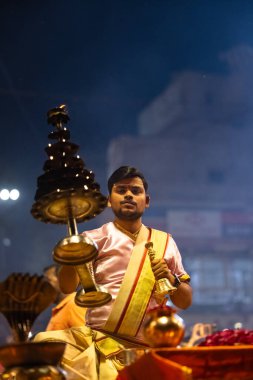 Varanasi, Uttar Pradesh, Hindistan - 3 Mart 2023: Ganga aarti, Dashashwamedh ghat geleneksel elbise ve Hindu ayinleri ile kutsal nehir ganges akşam aarti performans genç rahip portresi