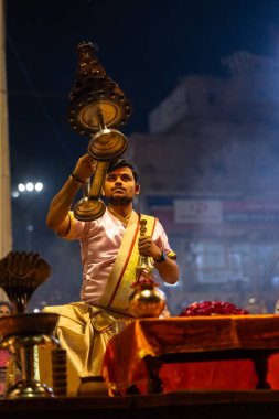 Varanasi, Uttar Pradesh, Hindistan - 3 Mart 2023: Ganga aarti, Dashashwamedh ghat geleneksel elbise ve Hindu ayinleri ile kutsal nehir ganges akşam aarti performans genç rahip portresi