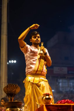Varanasi, Uttar Pradesh, Hindistan - 3 Mart 2023: Ganga aarti, Dashashwamedh ghat geleneksel elbise ve Hindu ayinleri ile kutsal nehir ganges akşam aarti performans genç rahip portresi