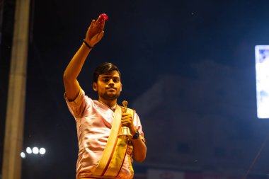 Varanasi, Uttar Pradesh, Hindistan - 3 Mart 2023: Ganga aarti, Dashashwamedh ghat geleneksel elbise ve Hindu ayinleri ile kutsal nehir ganges akşam aarti performans genç rahip portresi